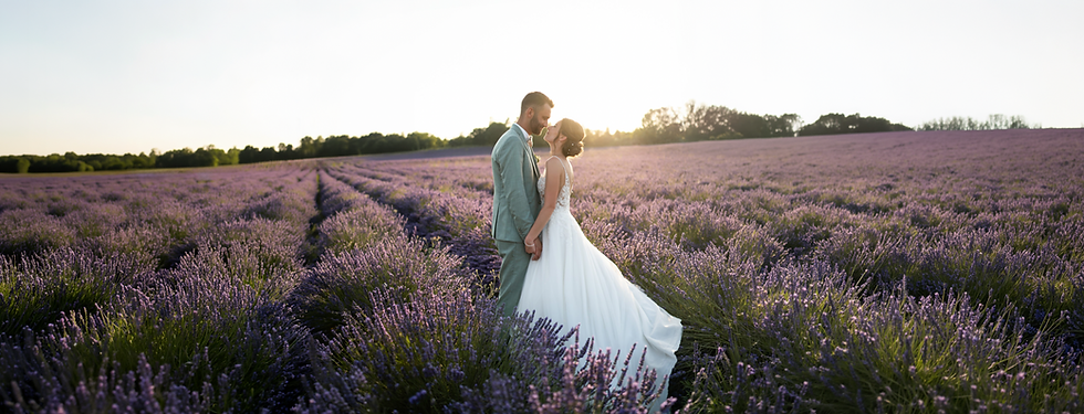 Couple de mariés dans un champ de lavande au coucher du soleil.