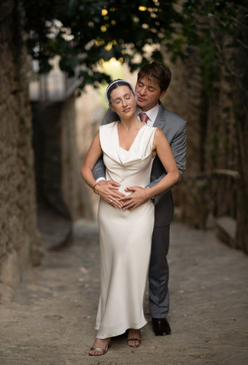 Un couple pose enlacé dans une ruelle bordée de façades en pierre en Provence