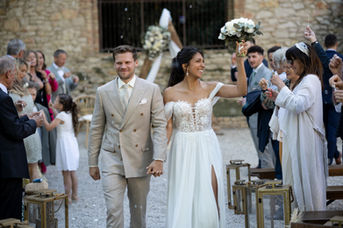 Couple mariés marchent, bras levés, entourés d'invités acclamant, PHOTOS DE MARIAGE, célébrant leur mariage.