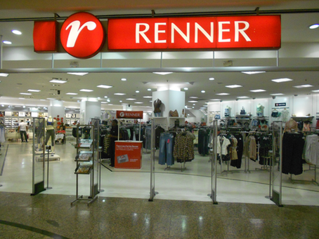 Fachada de uma loja da Lojas Renner em shopping center no Brasil, com vitrine de moda feminina e iluminação interna destacando a marca.