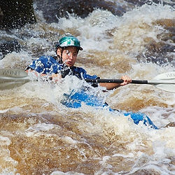 Des enfants joyeux en canoë-kayak, éclaboussant de l'eau tout en explorant les rivières paisibles du Jura en été.