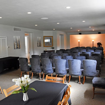 Memorial service room with rows of chairs and tables set for a gathering after cremation