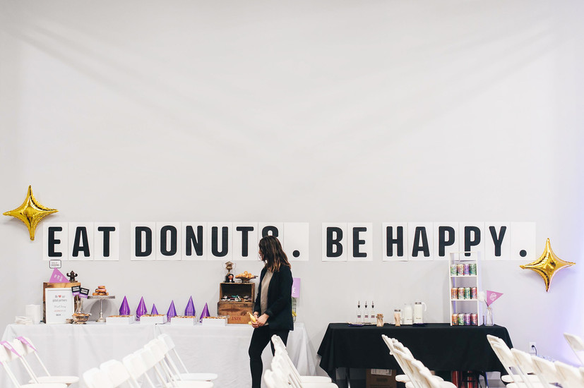 Clever wall signage at a breakfast event that says eat donuts, be happy