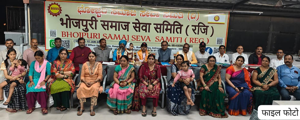 भोजपुरी समाज सेवा समिति की बैठक में मंच पर और सामने बैठे पुरुष–महिलाएँ, पीछे बड़ा बैनर, औपचारिक माहौल