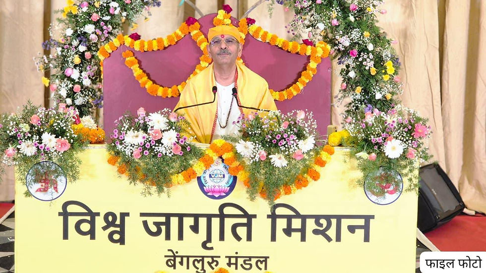 Man in yellow robes and turban speaks at a flower-decorated podium; banner reads विश्व जागृति मिशन बेंगलुरु मंडल.