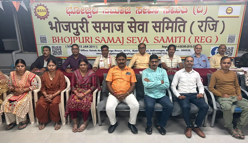 भोजपुरी समाज सेवा समिति के बैनर के सामने पुरुष व महिलाएँ कतार में बैठे, औपचारिक सभा का शांत माहौल।