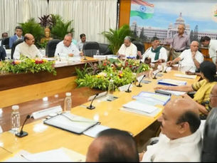 Government officials meet around a conference table with microphones, papers, flowers, and an Indian backdrop; फाइल फोटो