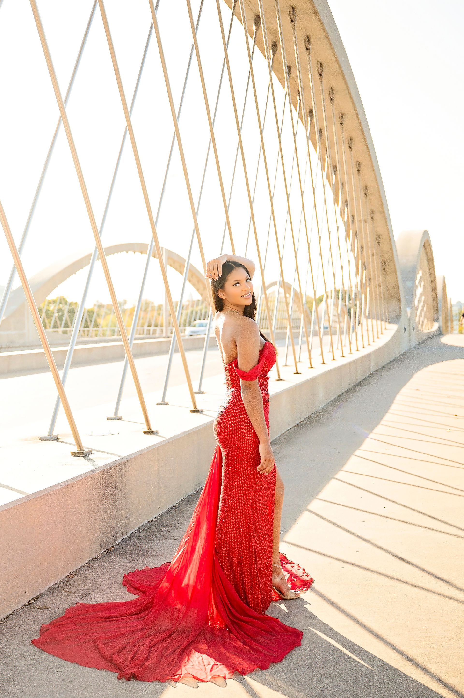 a girl wearing a red gown on a bridge in fort worth texas