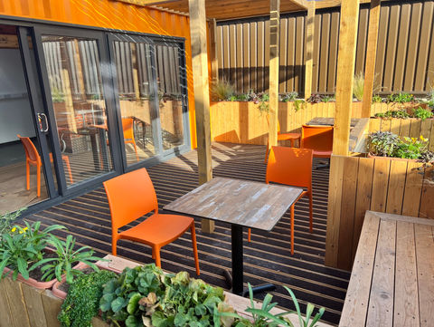 Outdoor seating area with tables and orange chairs, PLEYDELL SMITHYMAN commercial and industrial design. cafe design