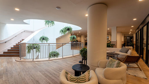 Spacious lounge area with staircase, curved balcony, seating and interior plants in Dundalk property