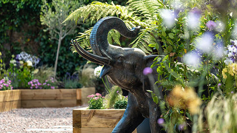 Garden sculpture surrounded by plants in landscaped garden.