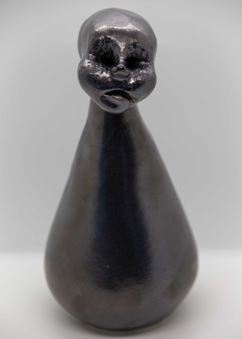 Hand modelled ceramic sculpture of human figure with cone shaped body, stoneware with metallic glaze.