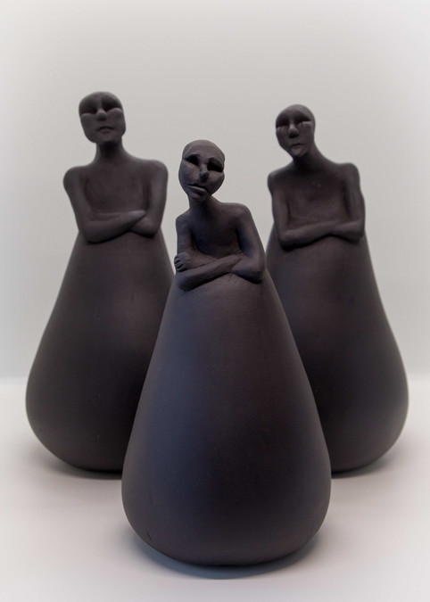 Hand modelled ceramic sculptures of human figures with cone shaped bodies, black stoneware.