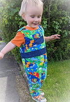 Toddler boy wearing dungarees in colourful dinosaur print cotton fabric handcrafted by Lavish Lilac
