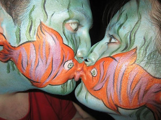 Couple painted with fish face paint design (in Cramlington) in orange, green and pink