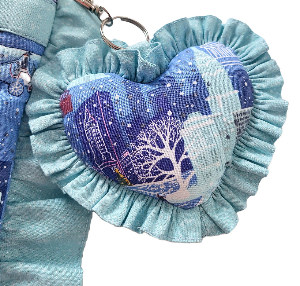 close up of heart shaped frilled bag charm in Fairytale in New York print in colours of blue, whit and silver