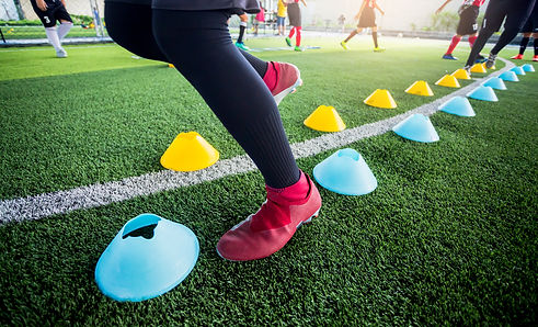 Soccer player Jogging and jump between cone markers on green artificial turf for soccer tr