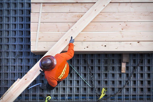 木板を持ち上げる建設作業員