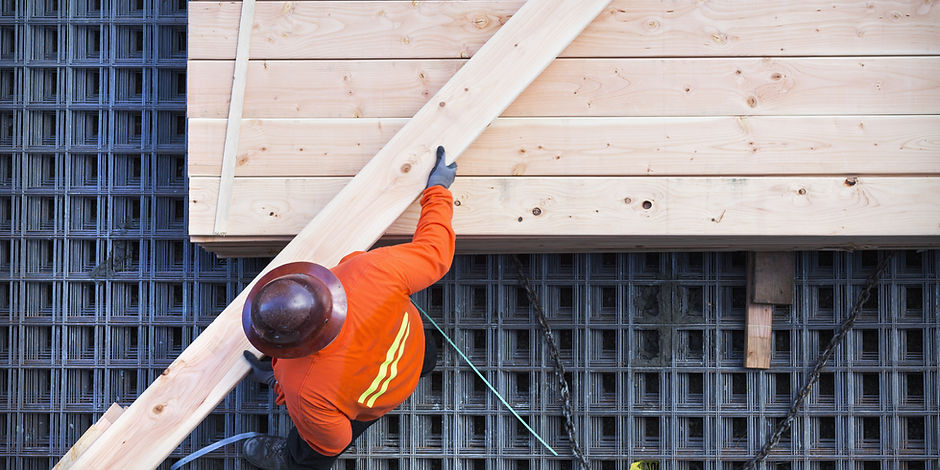 Construction worker lifting wood board