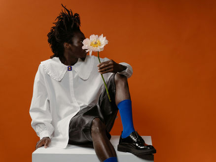 man with flower in a colourful outfit with blue socks