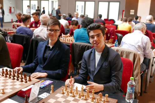 adam kozak with david gavrilescu in front of the chess boards