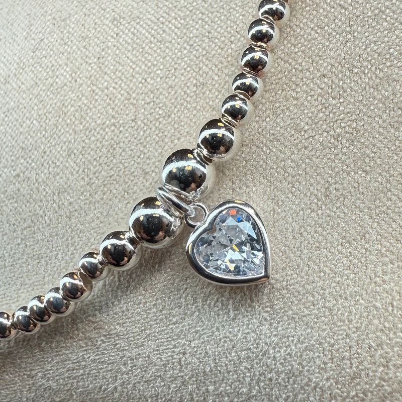 Thumbnail: Handmade beaded stacking bracelet featuring a clear heart charm and sterling silver accents