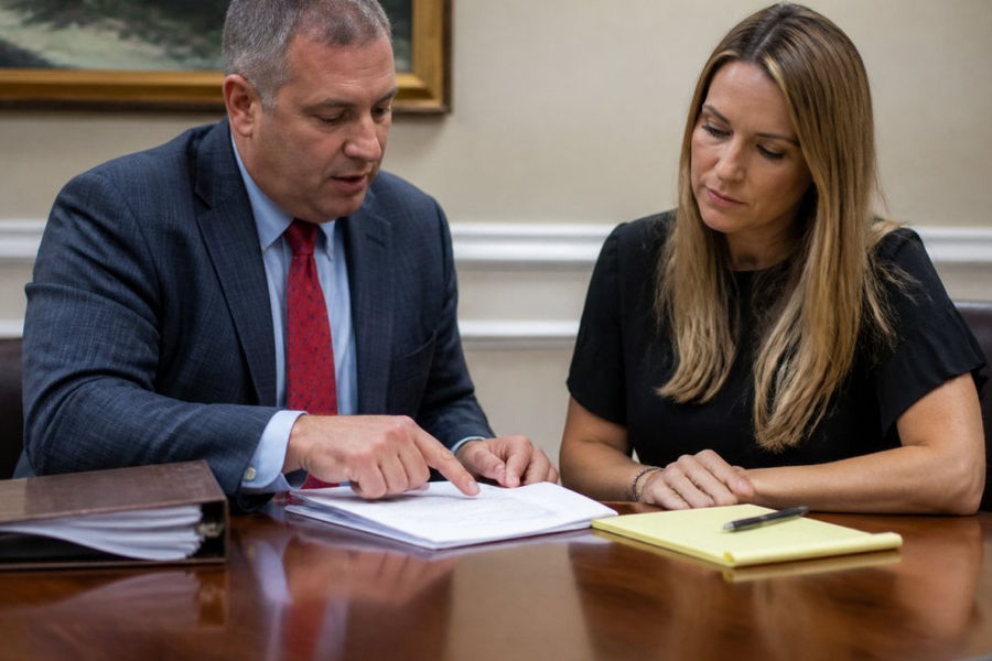 A defense attorney and client reviewing case documents together at a wooden conference table in a Maryland law office, legal papers and a notepad visible under warm overhead lighting