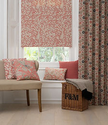 Made to measure Roman blinds in coral botanical fabric with detailed leaf and floral design, styled in a contemporary home setting.