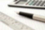 A ruler, pen, and calculator on graph paper