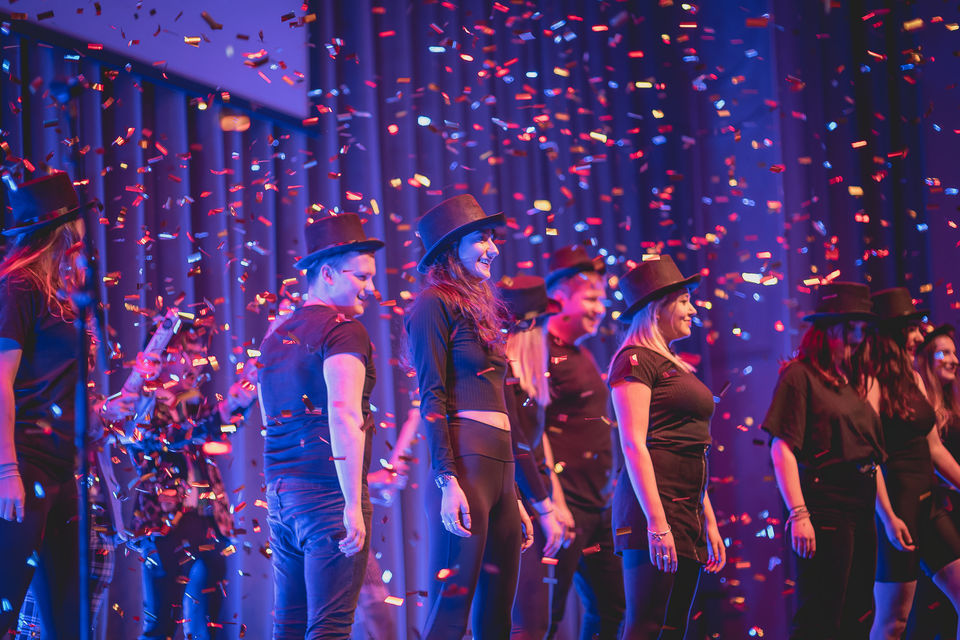 group of performers on stage showered in confetti
