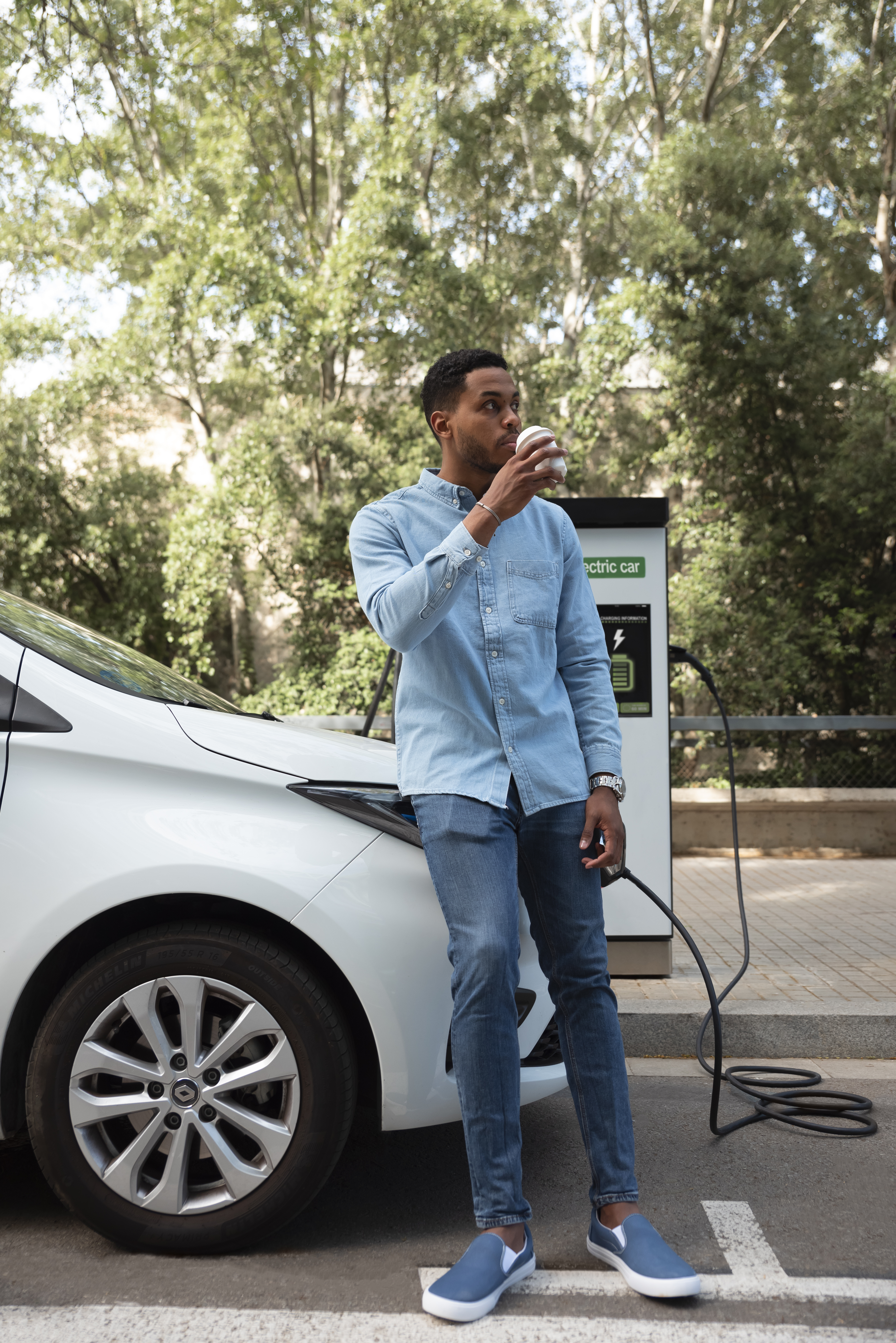 Individual enjoying a cup of coffee while their electric vehicle charges at a CARBER charging station, highlighting the convenience and leisure opportunities provided during charging