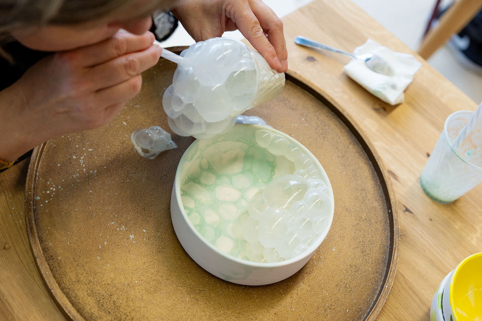 Eine Frau bläst Seifenblasen auf eine Rohkeramik im Keramik-Malatelier unique in Aarberg.