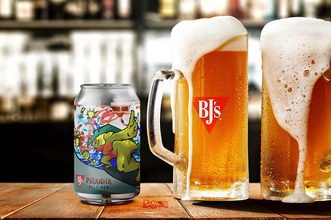 Piranha beer label on a can beside 2 large pitchers of beer on a bar table
