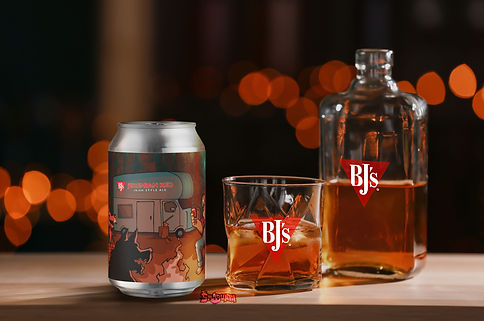 Jeremiah Red label on a beer can beside a glass and bottle with the BJ's logo on a dark table.