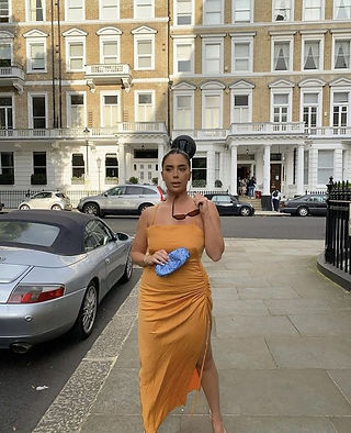 The Prop Pose - Woman fashion blogger wearing a bright orange summer dress posing with brown square sunglasses and a bright blue clutch handbag