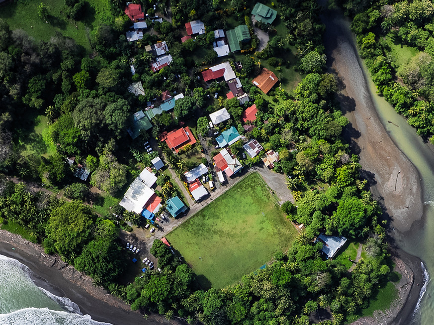 Aerial of waves breaking on coast with village and river mouth