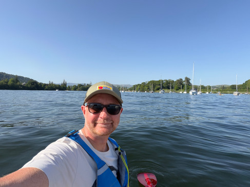 a man wearing sunglasses with a lake behind