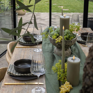 pale green led ester and erik colour candles on a wooden table with a green runner grapes and serve ware