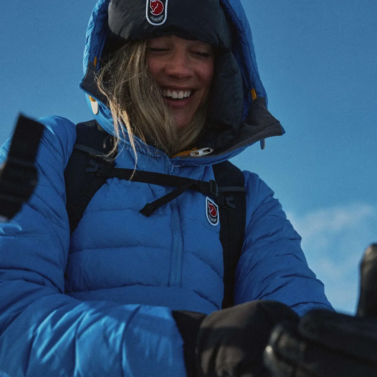 a lady in a blue fjallraven coat looking happy