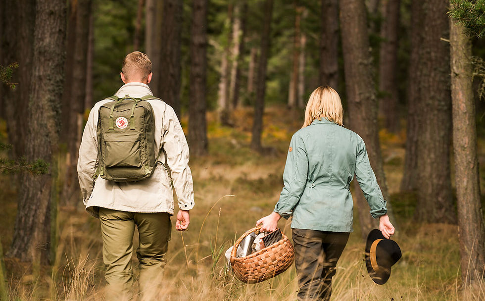 a man and a lady heading into the woods for a picnic the lady is holding a hat in her hand