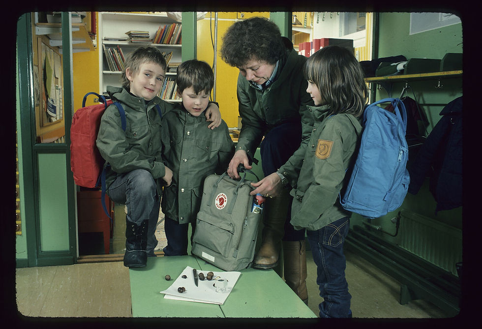 a teacher showing children how to pack their kanken