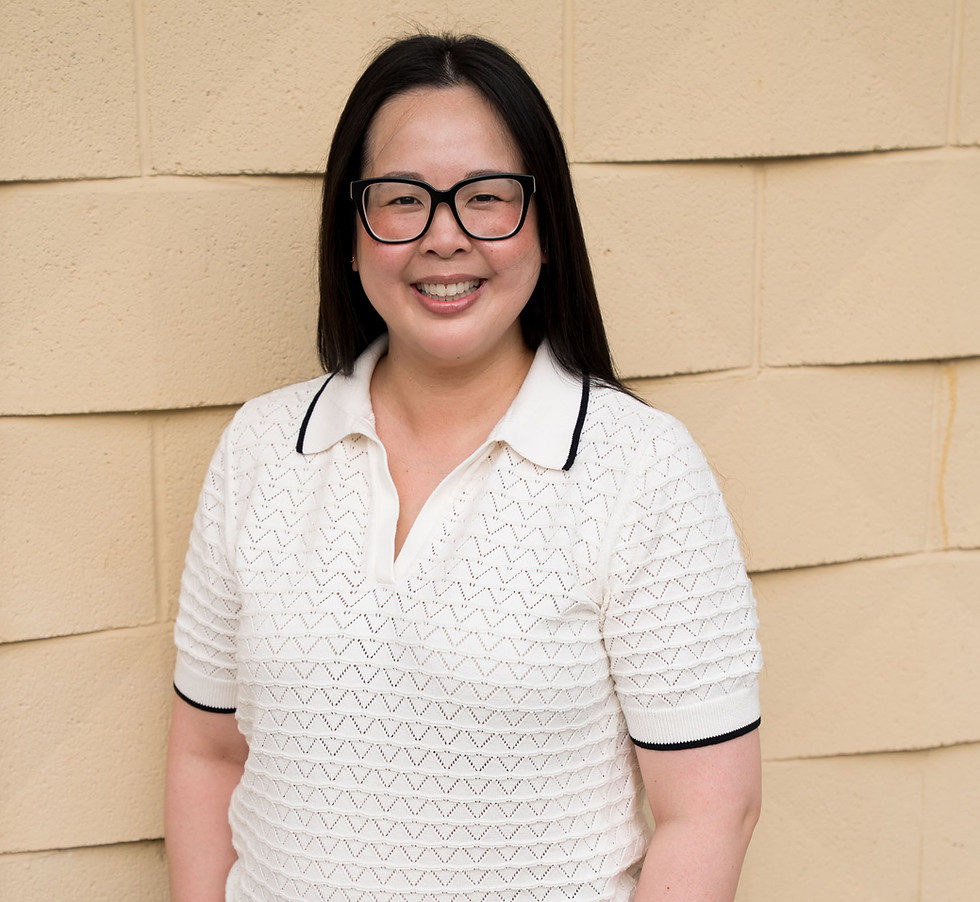 Anna Meksavanh standing in front of a yellow wall, with her hands in her pocket.