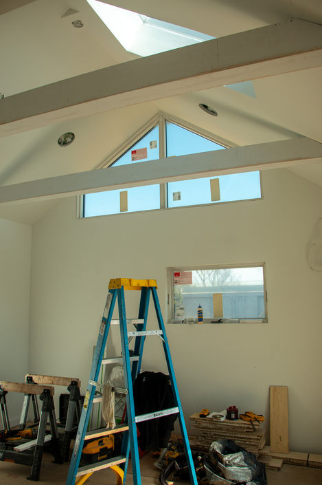 Room under construction with ladder and large windows.
