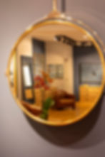 Vue de l'intérieur de la boutique Optique Fraysse reflétée dans un grand miroir rond.
