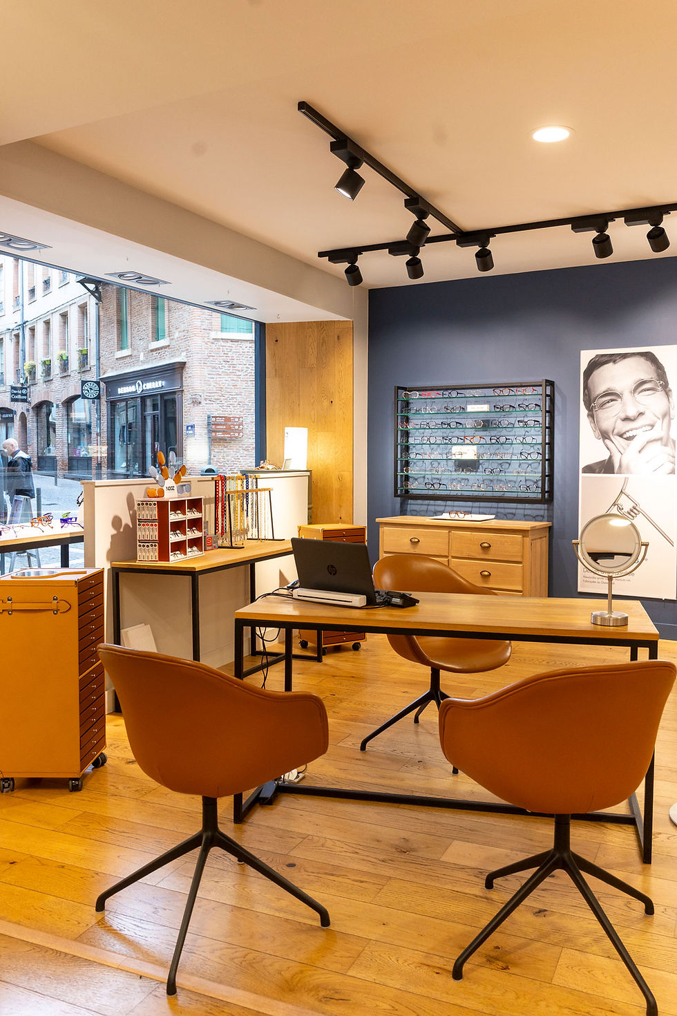 Ambiance intérieure moderne de l'opticien Optique Fraysse Albi avec mobilier en bois et assises oranges.