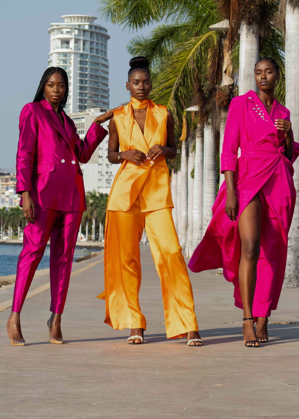 3 outfits: a full suit in silk pink with swarovski buttons on the blazer. A tailored blazer vest with leg-wide pants in silk orange. A silk pink long dress