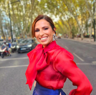 Joana Cruz wearing a dark blue sillk skirt and a red silk blouse with a big bow in a street in Lisbon