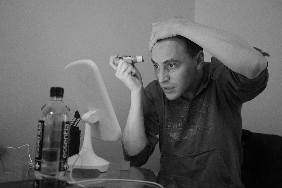 drag queen applying glue to eyebrows