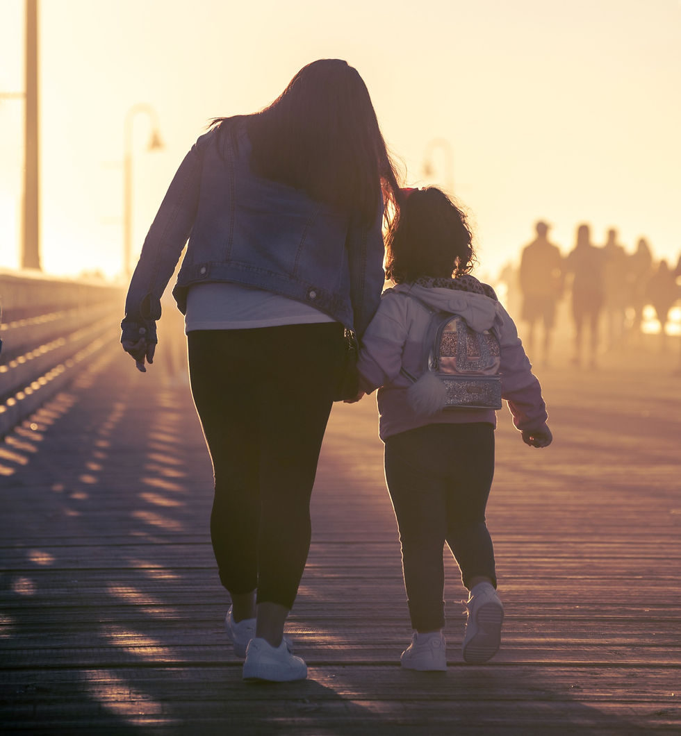 Mother and daughter walking hands on boardwalk