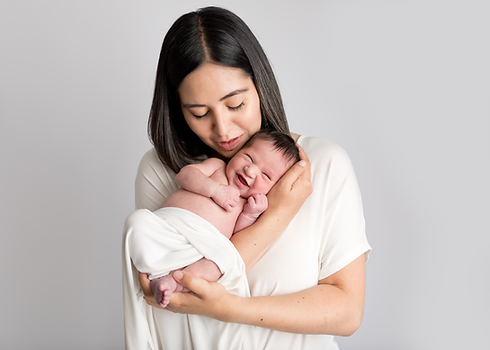 a smiling newborn being held by their mother